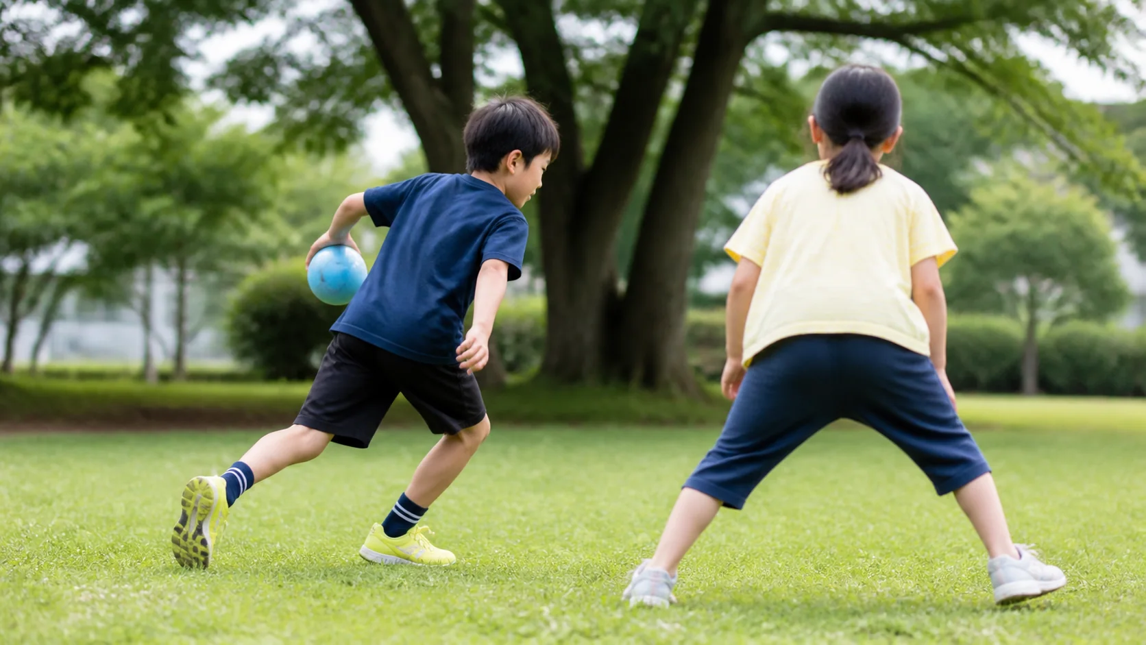 公園でボールを見ながら相手を避けて動く日本人の子どもたち
