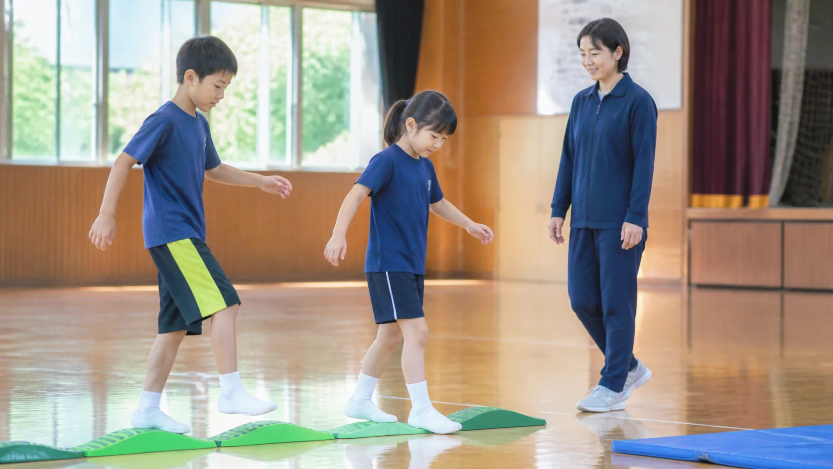 体育館で年齢の異なる日本人の子どもたちを見守る大人